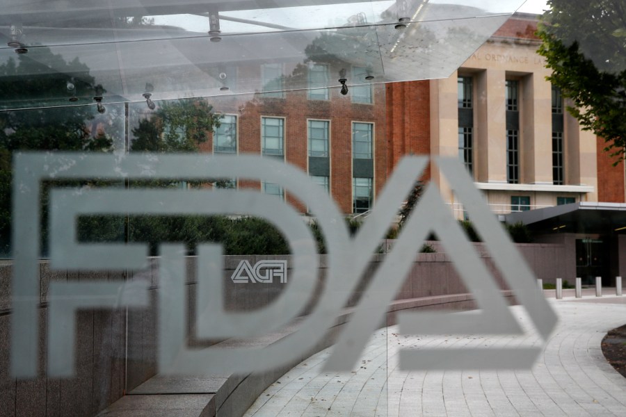 This Aug. 2, 2018, file photo shows the U.S. Food and Drug Administration building behind FDA logos at a bus stop on the agency's campus in Silver Spring, Md. In a report to Congress and an accompanying “playbook” for states and localities, key federal health agencies and the Defense Department sketched out complex plans for a vaccination campaign to begin gradually early next year or later in 2020, eventually ramping up to reach any American who wants a shot. The Pentagon is involved with the distribution of vaccines, but civilian health workers will be the ones giving shots. (AP Photo/Jacquelyn Martin, File)