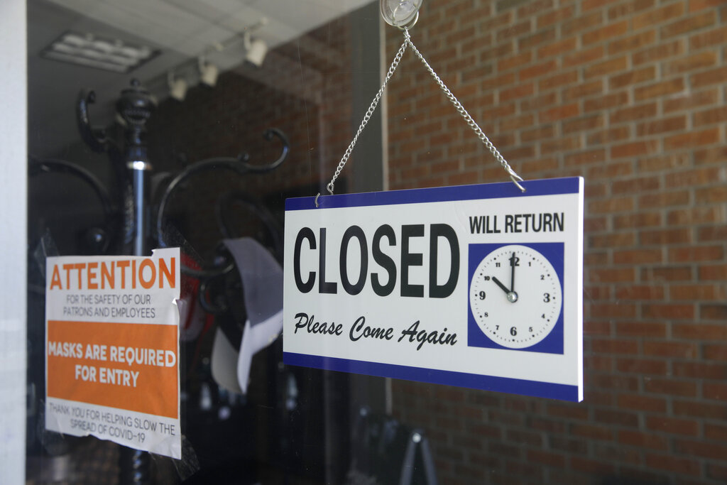 In this July 18, 2020 file photo a closed sign hangs in the window of a barber shop in Burbank, Calif. (AP Photo/Marcio Jose Sanchez, File)