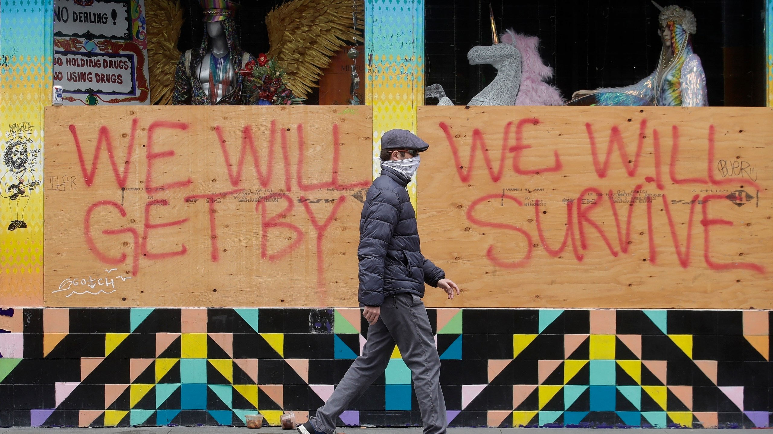 A man wears a face mask while walking past signs posted over windows of a store in the Haight-Ashbury district in San Francisco, Saturday, April 18, 2020. California's death count from the coronavirus surpassed 15,000 on Sunday, Sept. 20, even as the state saw widespread improvement in infection levels. (AP Photo/Jeff Chiu)