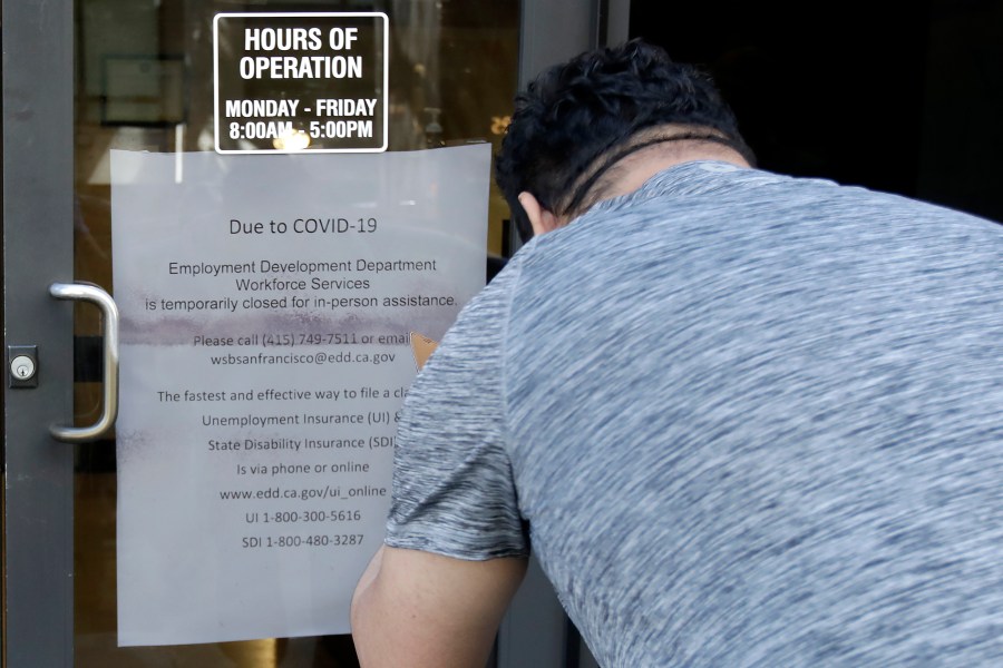 A man takes a photo of a sign advising that the Employment Development Department is closed due to coronavirus concerns in San Francisco on March 26, 2020. (Jeff Chiu / Associated Press)