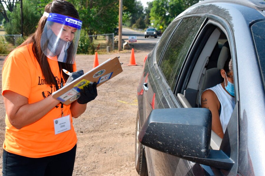 In this Aug. 26, 2020, file photo, Lauri Dawn Kindness, left, helps a family participate in the U.S. Census as part of a campaign to increase Native American participation in the count, on the Crow Indian Reservation, in Lodge Grass, Montana. (AP Photo/Matthew Brown, File)