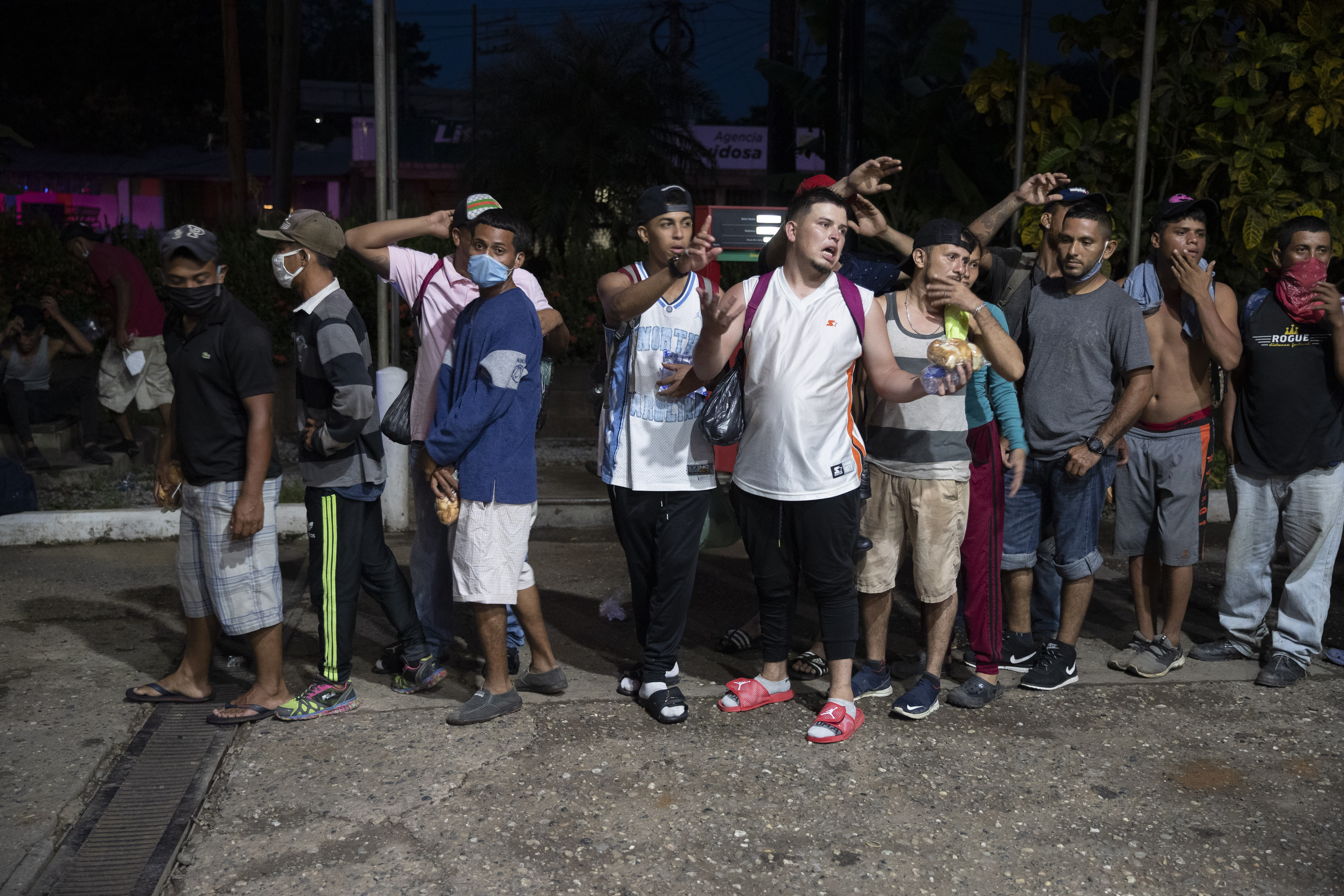 Migrants from Honduras stand in line waiting for aid during their journey to the United States-Mexican border, in Morales, Guatemala, Thursday, Oct. 1, 2020. (AP Photo/Moises Castillo)