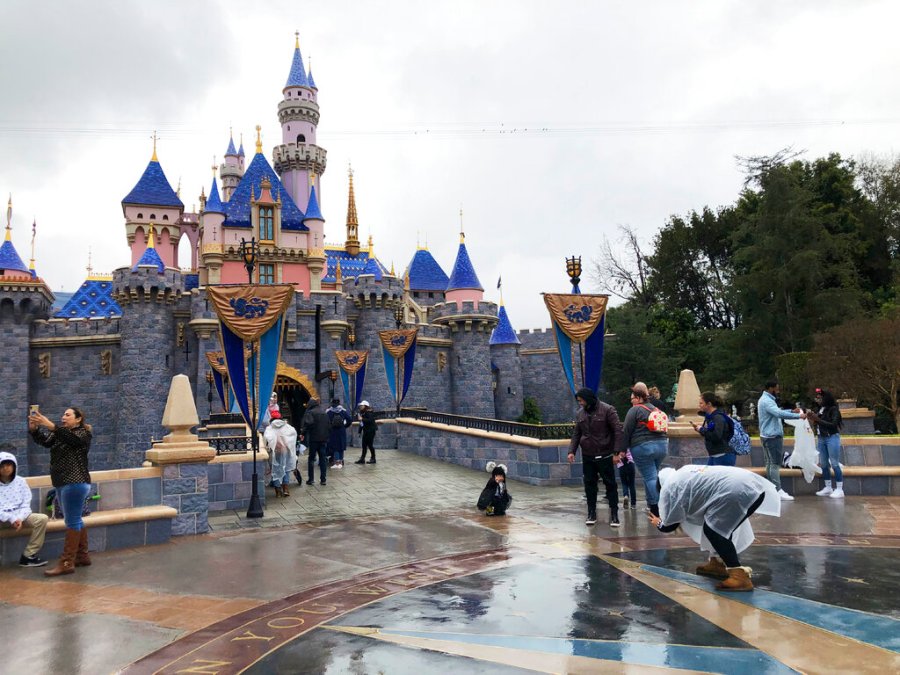 In this March 13, 2020 file photo, visitors take photos at Disneyland in Anaheim. (AP Photo/Amy Taxin, File)