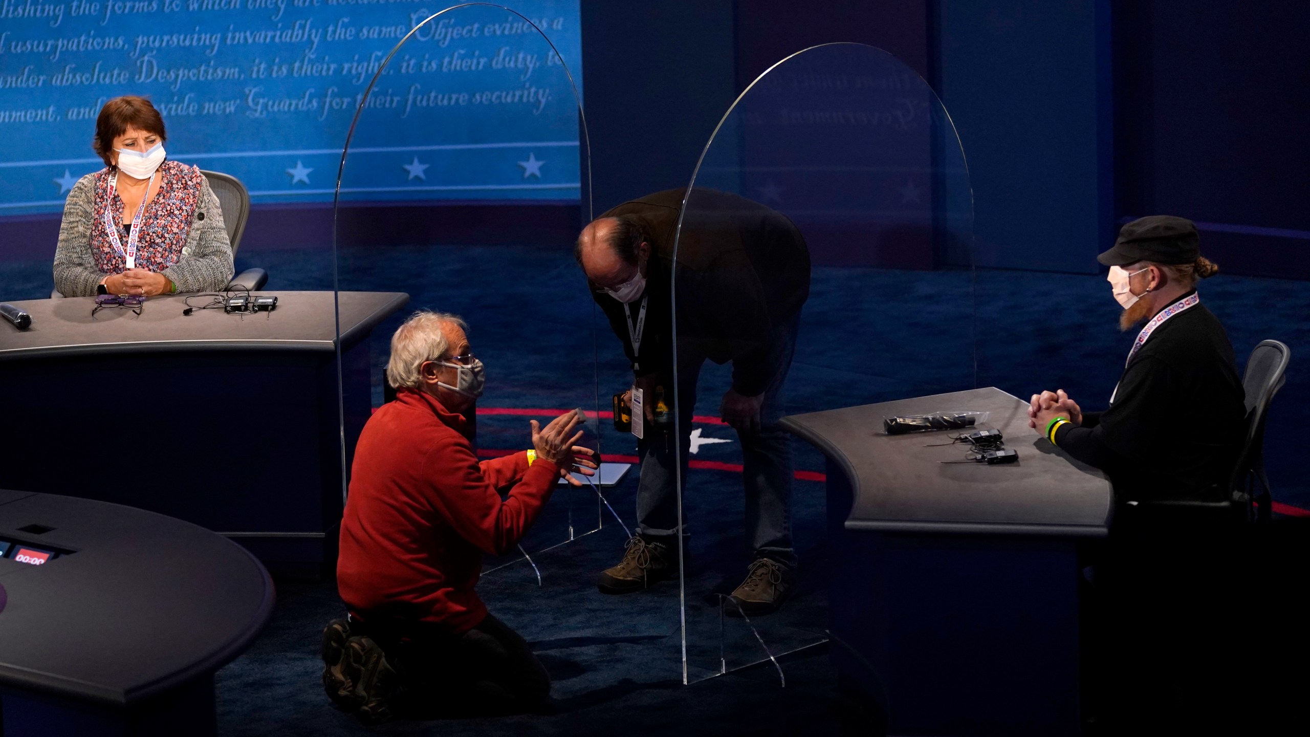 Members of the production crew stand in on the stage near plexiglass barriers which will serve as a way to protect the spread of COVID-19 as preparations take place for the vice presidential debate at the University of Utah, Tuesday, Oct. 6, 2020, in Salt Lake City. The vice presidential debate between Vice President Mike Pence and Democratic vice presidential candidate Sen. Kamala Harris, D-Calif., is scheduled for Oct. 7. (AP Photo/Julio Cortez)