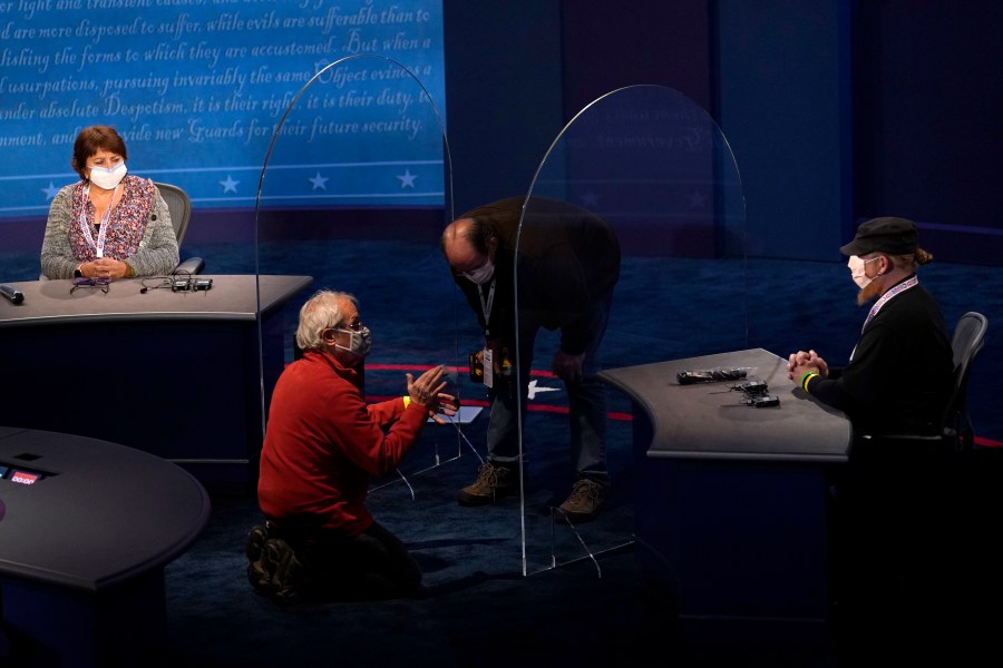 Members of the production crew stand in on the stage near plexiglass barriers which will serve as a way to protect the spread of COVID-19 as preparations take place for the vice presidential debate at the University of Utah, Tuesday, Oct. 6, 2020, in Salt Lake City. The vice presidential debate between Vice President Mike Pence and Democratic vice presidential candidate Sen. Kamala Harris, D-Calif., is scheduled for Oct. 7. (AP Photo/Julio Cortez)