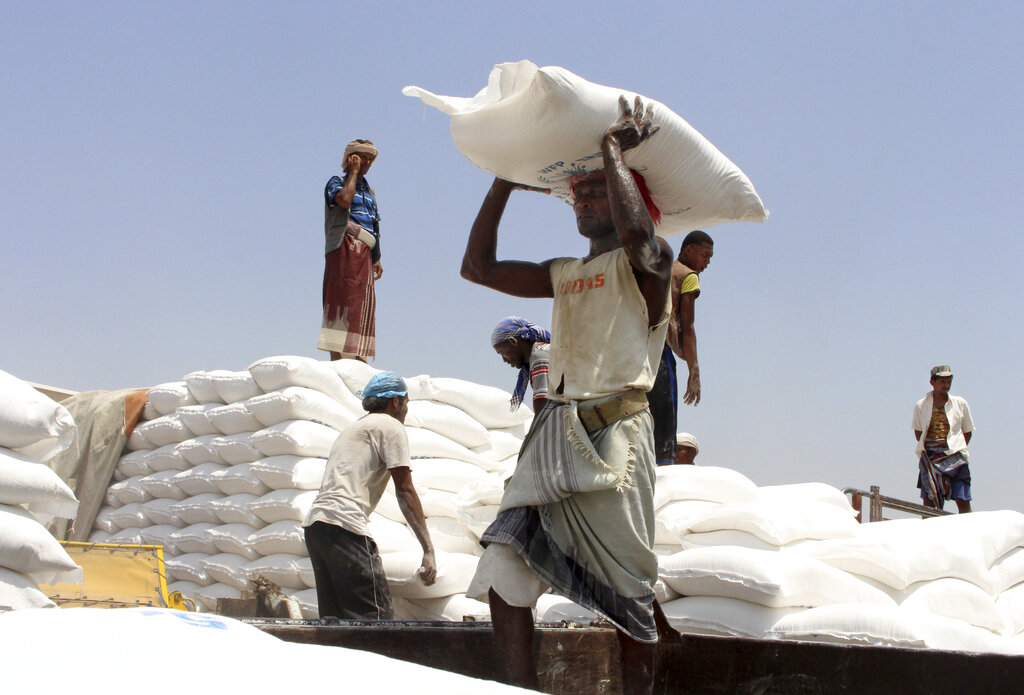 In this Sept. 21, 2018 file photo, men deliver U.N. World Food Program (WFP) aid in Aslam, Hajjah, Yemen. (AP Photo/Hammadi Issa, File)