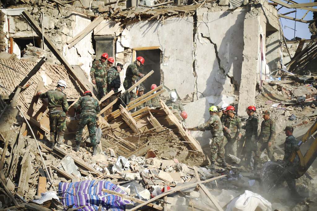 Rescuers work at the scene of damage after shelling by Armenian's artillery during fighting over the separatist region of Nagorno-Karabakh, in Ganja, Azerbaijan, Sunday, Oct. 11, 2020. (AP Photo/Aziz Karimov)