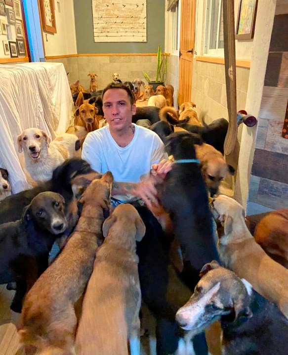 In this Oct. 7, 2020, photo provided by Daniela Rojas, Ricardo Pimentel plays with dogs that he sheltered at his home in Leona Vicario, Mexico, during Hurricane Delta. (Daniela Rojas via AP)