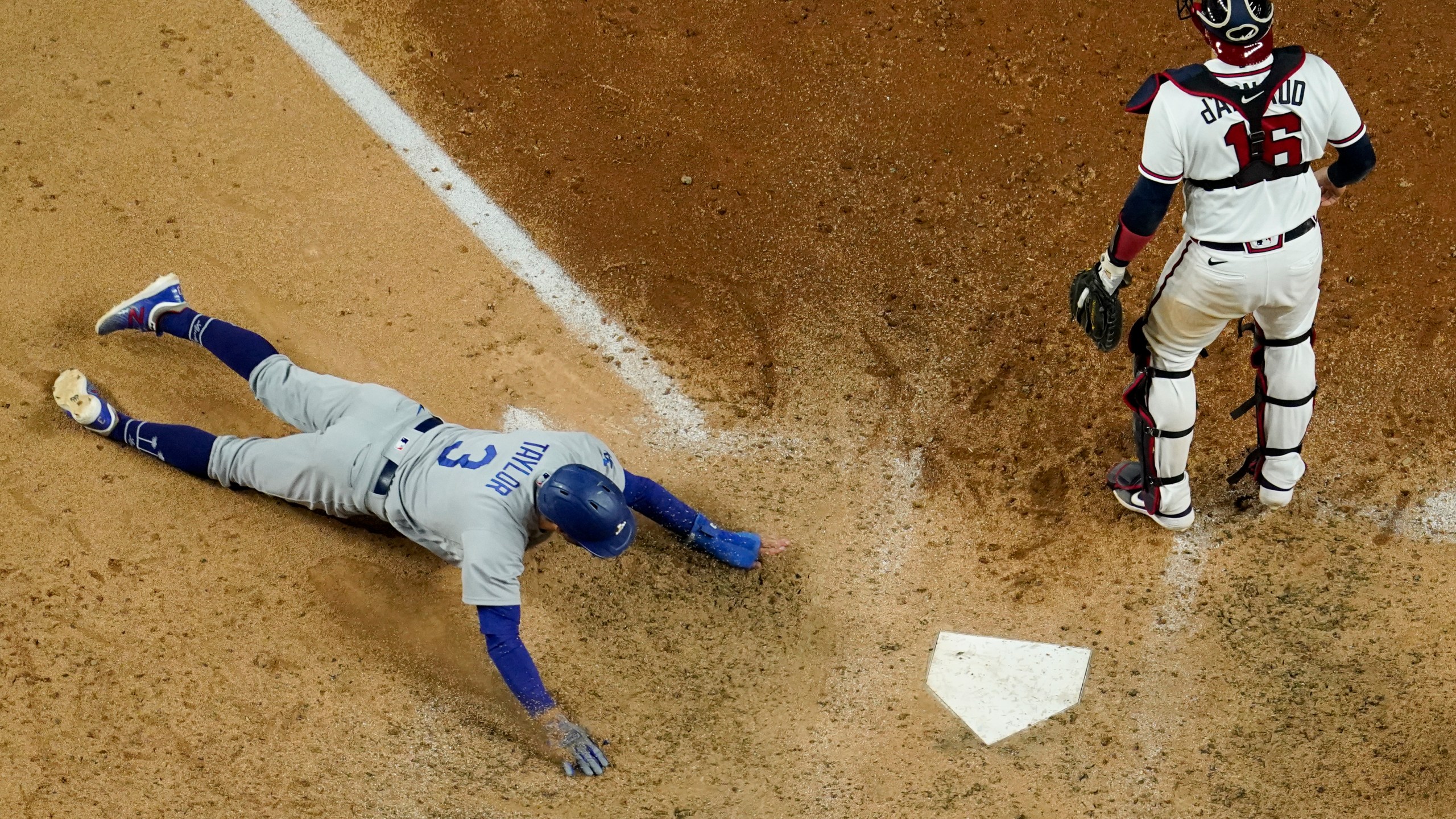 Los Angeles Dodgers' Chris Taylor scores past Atlanta Braves catcher Travis d'Arnaud on a hit by Mookie Betts during the seventh inning in Game 5 of a baseball National League Championship Series Friday, Oct. 16, 2020, in Arlington, Texas. (AP Photo/David J. Phillip)