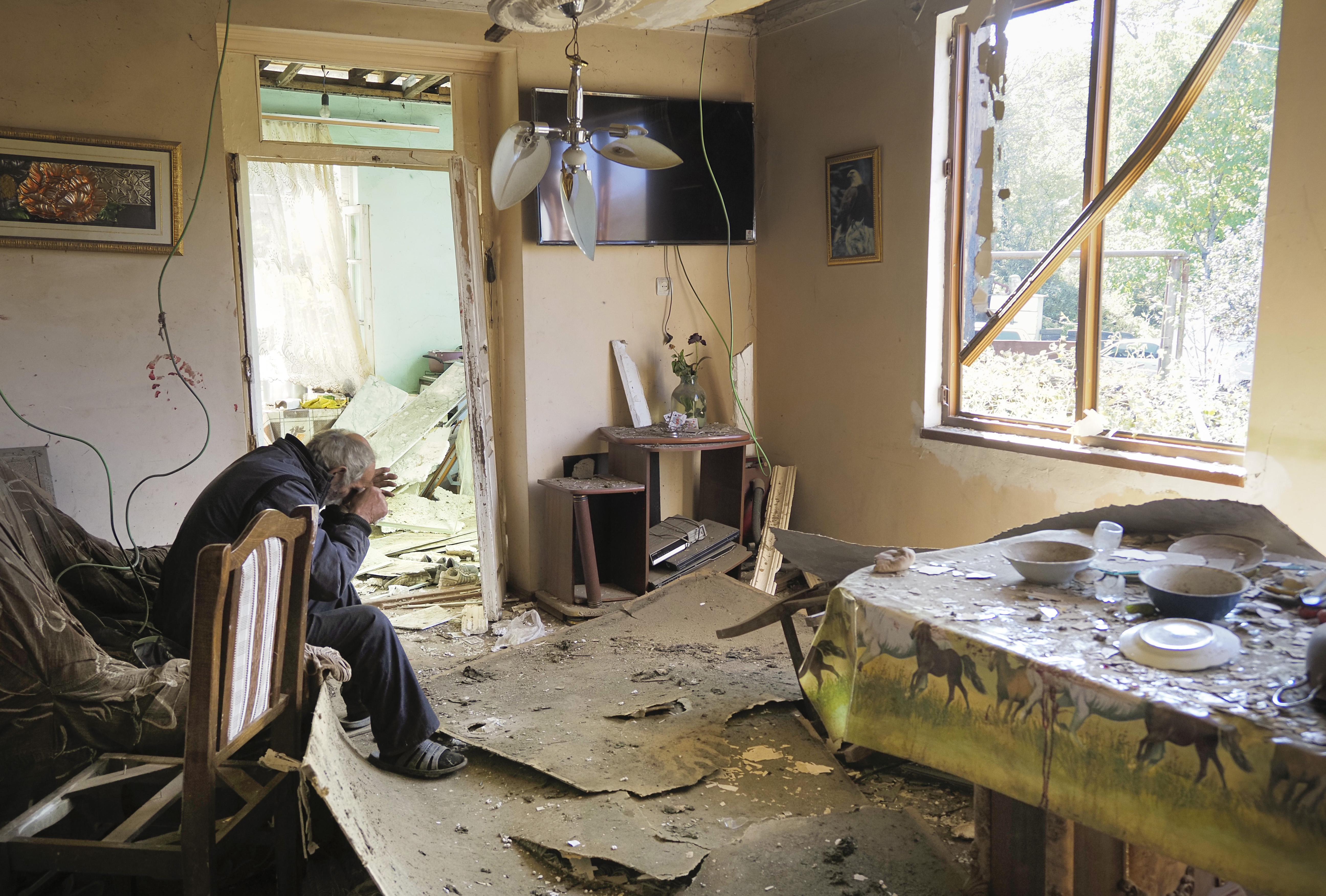 Yury Melkonyan, 64, sits in his house damaged by shelling from Azerbaijan's artillery during a military conflict in Shosh village outside Stepanakert, the capital of Nagorno-Karabakh on Oct. 17, 2020. (AP Photo)