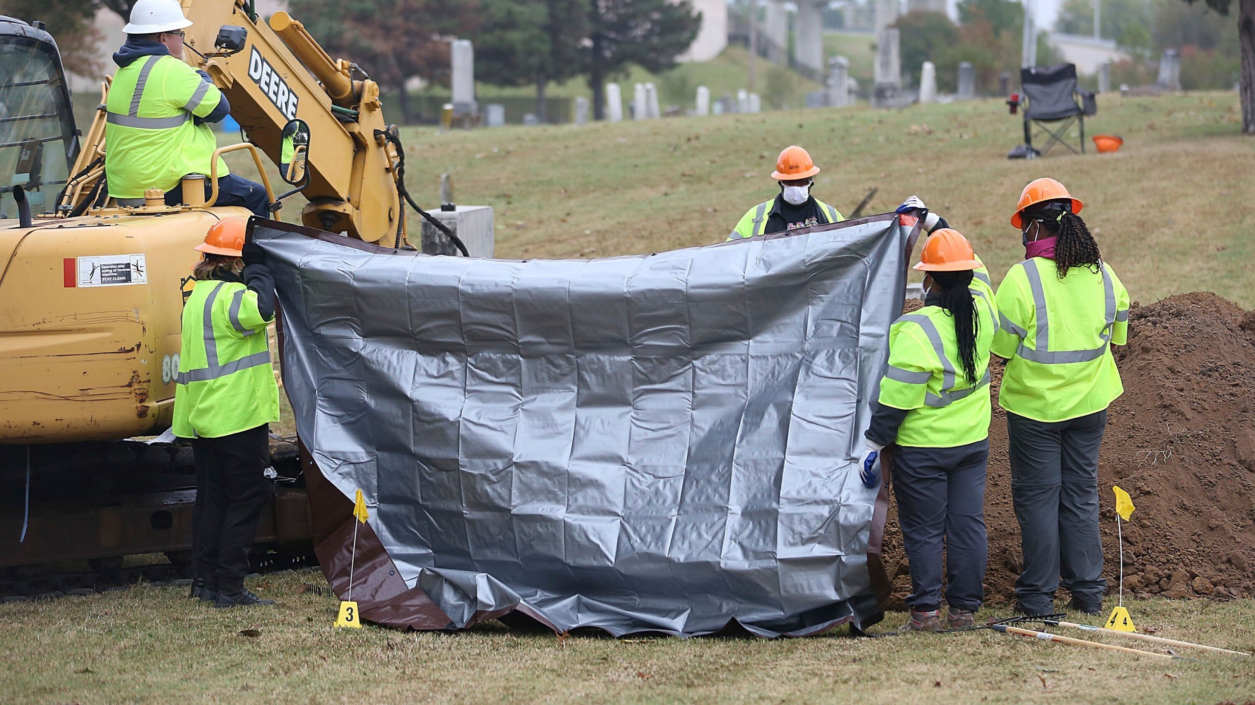 Workers hold up tarps to block spectators' views during a second test excavation and core sampling, Tuesday, Oct. 20, 2020, in the search for remains at Oaklawn Cemetery in Tulsa, Okla., from the 1921 Tulsa Race Massacre. (Mike Simons/Tulsa World via AP)