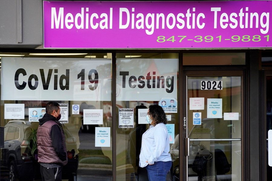 In this Oct. 21, 2020, file photo, Exam Corp Lab employee, right, wears a mask as she talks with a patient lined up for COVID-19 testing in Niles, Ill. The United States is approaching a record for the number of new daily coronavirus cases in the latest ominous sign about the disease's grip on the nation. (AP Photo/Nam Y. Huh, File)