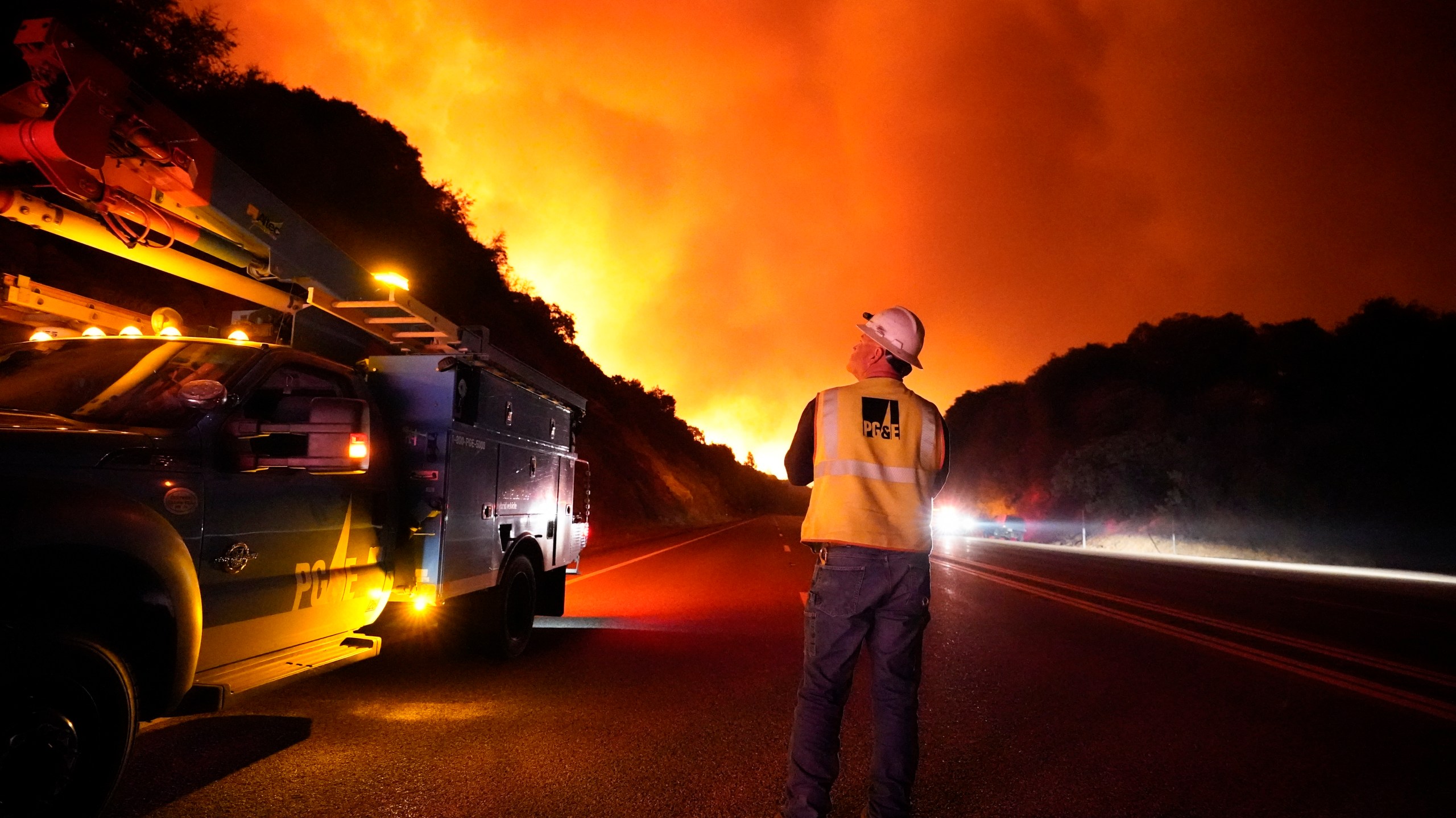 In this Sept. 8, 2020, file photo, a Pacific Gas and Electric worker looks up at the advancing Creek Fire along Highway 168 near Alder Springs, Calif.(AP Photo/Marcio Jose Sanchez, File)