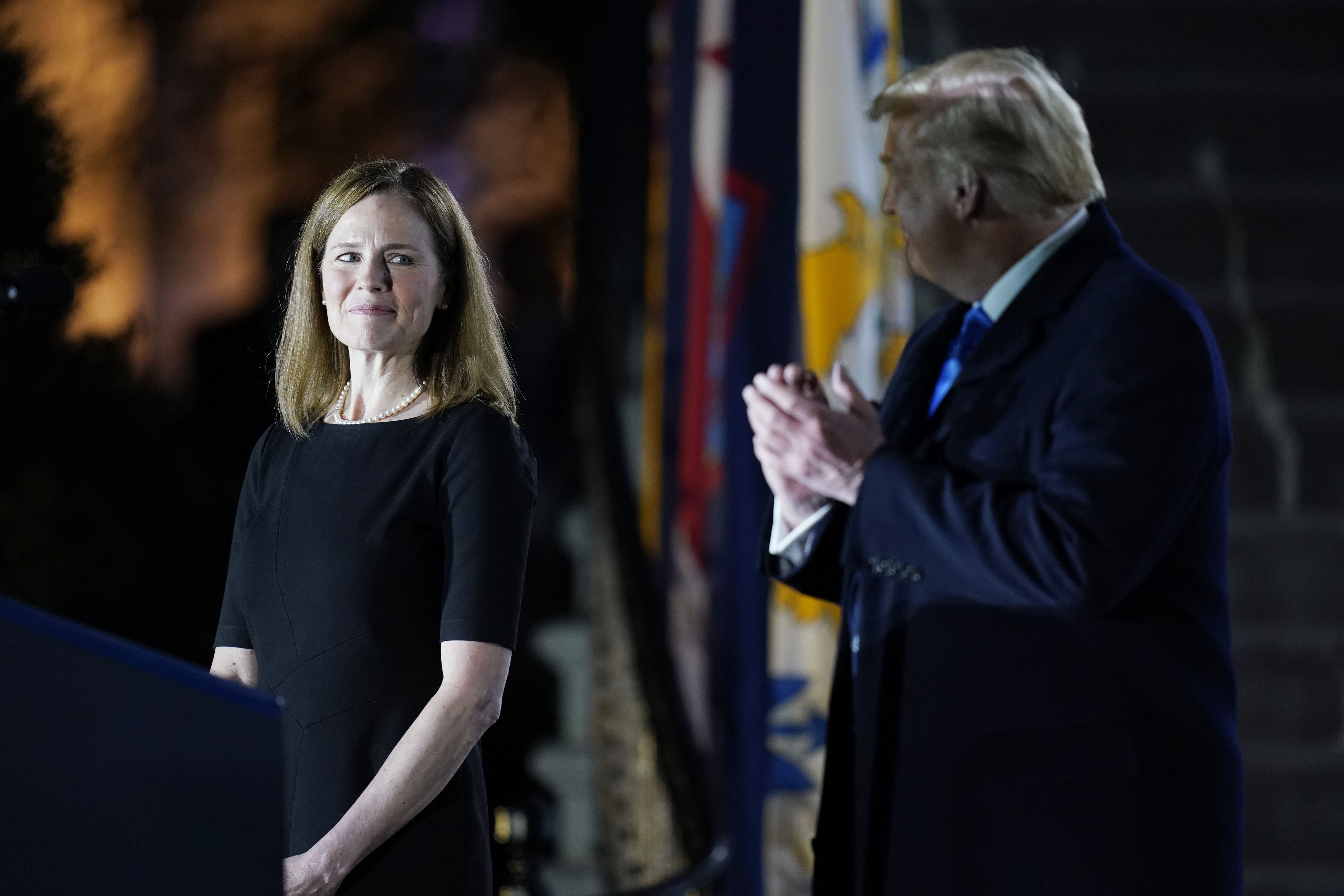 President Donald Trump looks toward Amy Coney Barrett, before Supreme Court Justice Clarence Thomas administers the Constitutional Oath to her on the South Lawn of the White House on Oct. 26, 2020, after Barrett was confirmed by the Senate earlier in the evening. (Patrick Semansky / Associated Press)