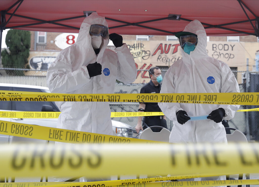 In this Monday, April 20, 2020, file photo members with Los Angeles Fire Department wear protective equipment at a COVID-19 testing site in the Skid Row district in Los Angeles. (AP Photo/Marcio Jose Sanchez, File)