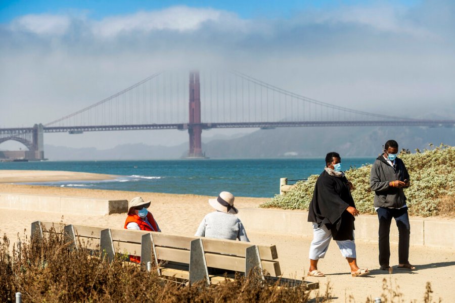 With the Golden Gate Bridge in the background, walkers wear masks while strolling at Crissy Field East Beach in San Francisco on Oct. 22, 2020. (AP Photo/Noah Berger)