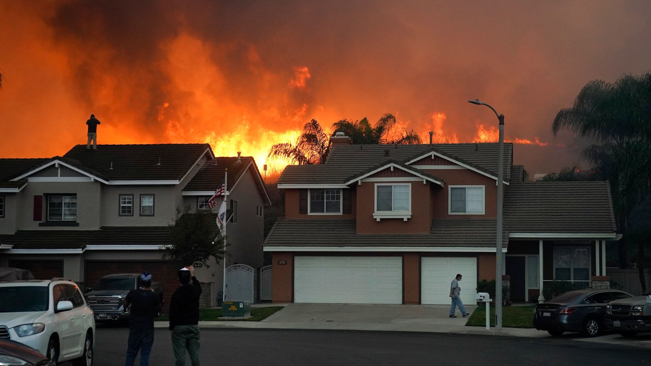 Residents watch as the Blue Ridge Fire burns along the hillside Tuesday, Oct. 27, 2020, in Chino Hills, Calif. Facing extreme wildfire conditions this week that included hurricane-level winds, the main utility in Northern California cut power to nearly 1 million people while its counterpart in Southern California pulled the plug on just 30 customers to prevent power lines and other electrical equipment from sparking a blaze. (AP Photo/Jae C. Hong)