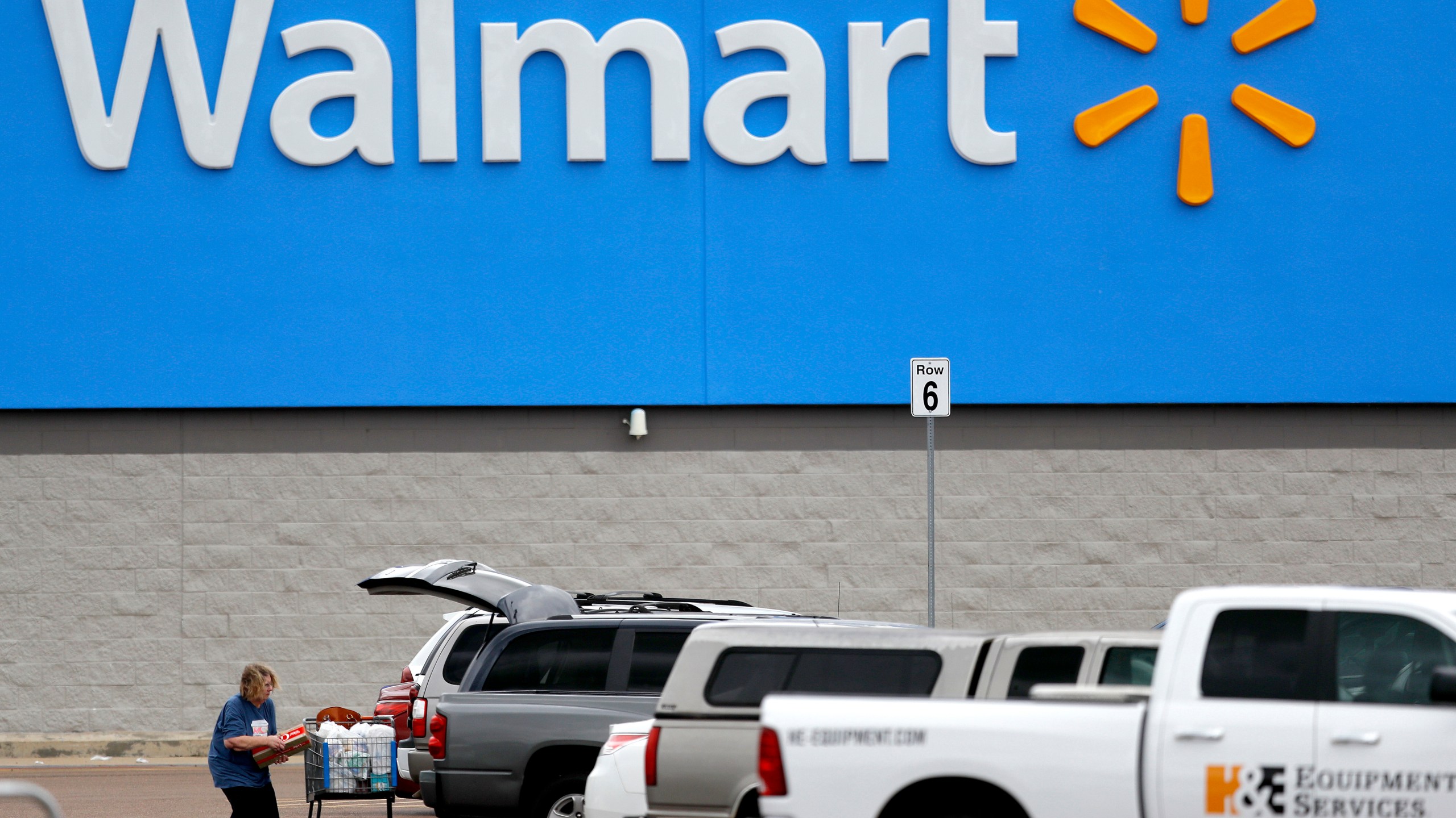 In this March 31, 2020 file photo, a woman pulls groceries from a cart to her vehicle outside of a Walmart store in Pearl, Miss. (AP Photo/Julio Cortez, File)