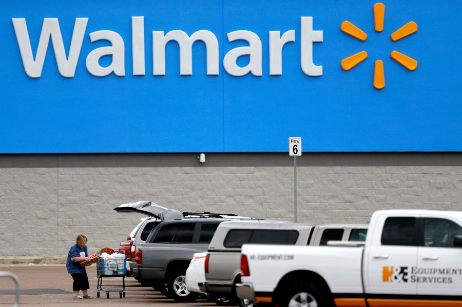 In this March 31, 2020 file photo, a woman pulls groceries from a cart to her vehicle outside of a Walmart store in Pearl, Miss. (AP Photo/Julio Cortez, File)