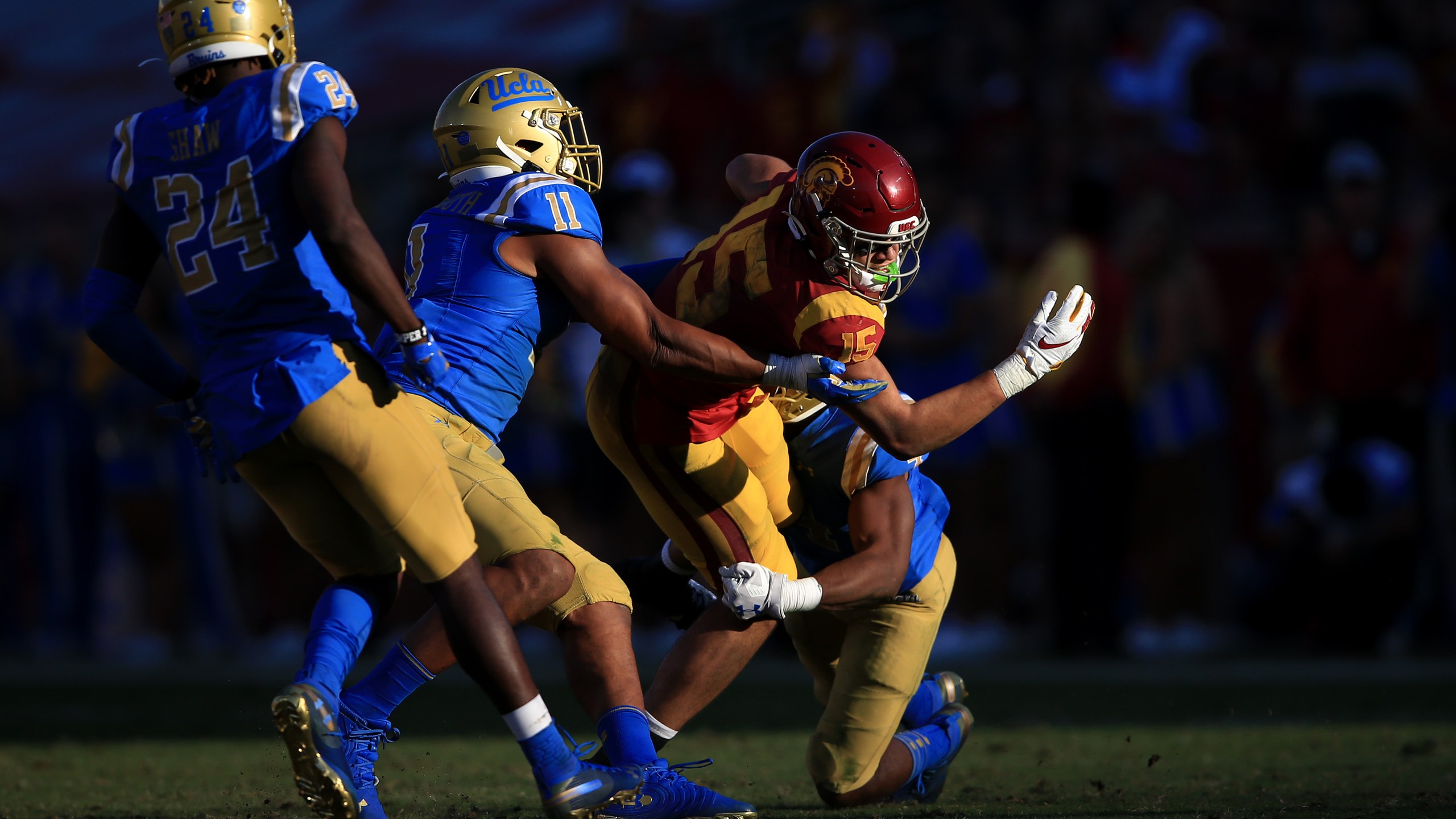 Stephan Blaylock #4, Drake London #15 of the USC Trojans is tackled by Keisean Lucier-South #11 and Jay Shaw #24 of the UCLA Bruins during the second half of a game at Memorial Coliseum on Nov. 23, 2019 in Los Angeles. (Sean M. Haffey/Getty Images)