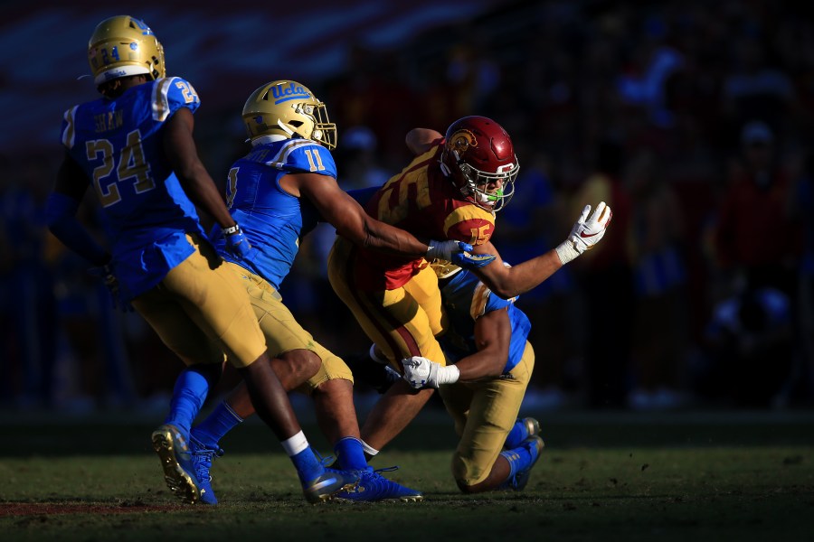 Stephan Blaylock #4, Drake London #15 of the USC Trojans is tackled by Keisean Lucier-South #11 and Jay Shaw #24 of the UCLA Bruins during the second half of a game at Memorial Coliseum on Nov. 23, 2019 in Los Angeles. (Sean M. Haffey/Getty Images)