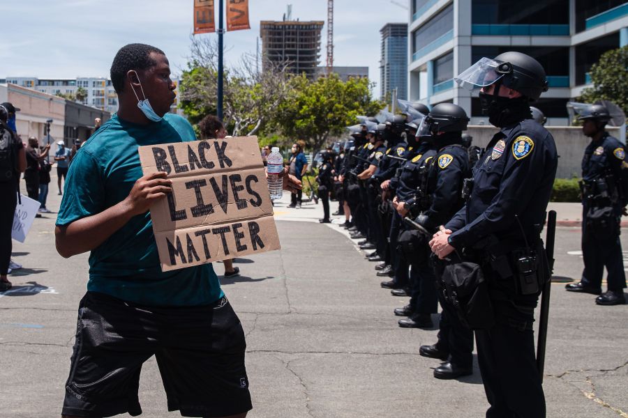 A man holds a Black Lives Matter sign in front of the San Diego Police in downtown San Diego, California on May 31, 2020. (ARIANA DREHSLER/AFP via Getty Images)