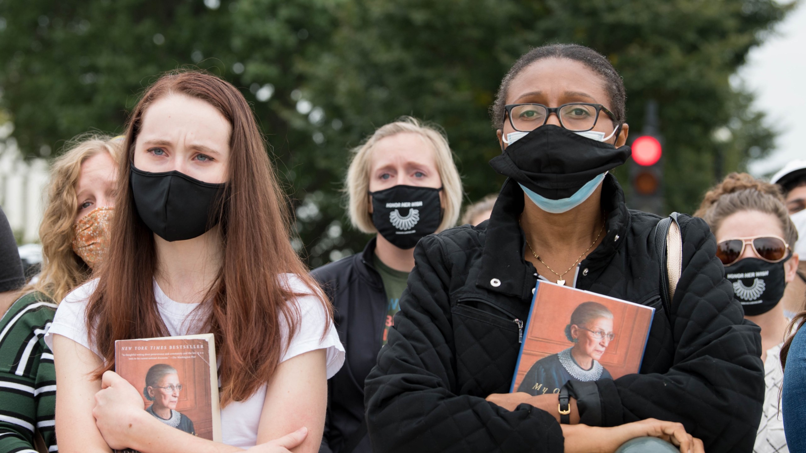 Women hold Justice Ruth Bader Ginsburg's book as they watch as her casket is carried down the steps of the U.S. Capitol on Sept. 25, 2020. (Liz Lynch / Getty Images)