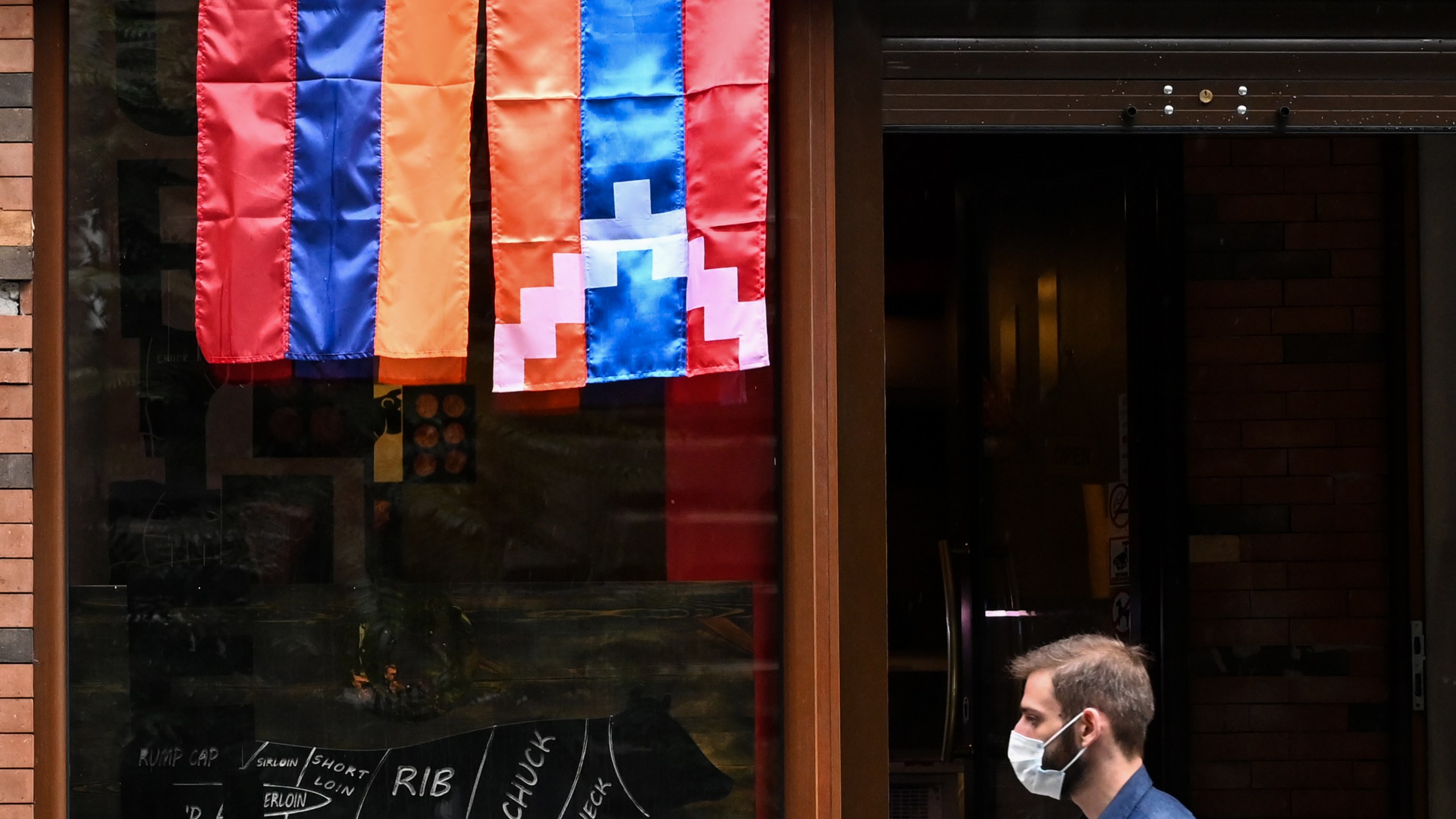 A man walks past a shop decorated with flags of Armenia and the breakaway Nagorno-Karabakh region in Yerevan, Armenia's capital, on Oct. 6, 2020. (AFP via Getty Images)