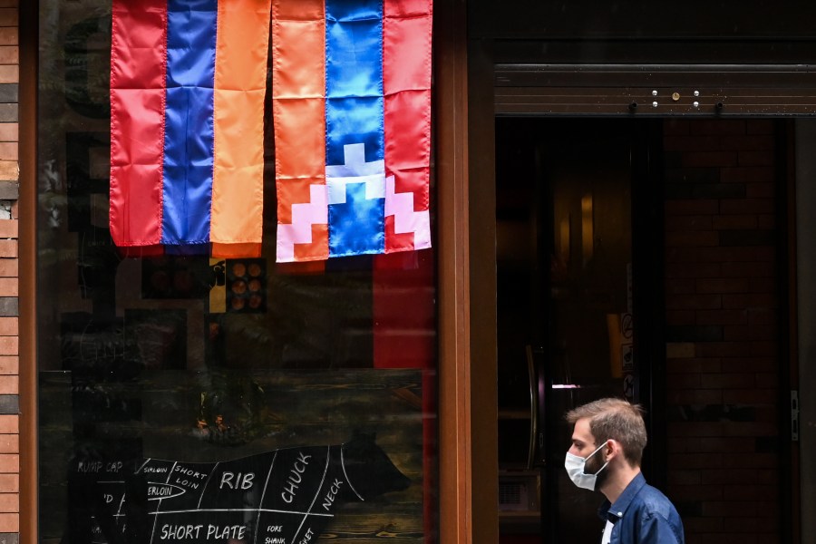 A man walks past a shop decorated with flags of Armenia and the breakaway Nagorno-Karabakh region in Yerevan, Armenia's capital, on Oct. 6, 2020. (AFP via Getty Images)