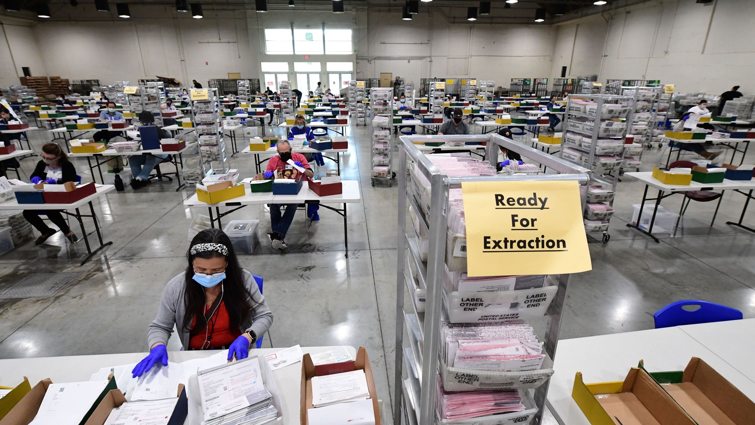 Election workers extract mail-in ballots from their envelopes and examine the ballot for irregularities at the Los Angeles County Registrar Recorders' mail-in ballot processing center at the Pomona Fairplex in Pomona on Oct. 28, 2020. (ROBYN BECK/AFP via Getty Images)