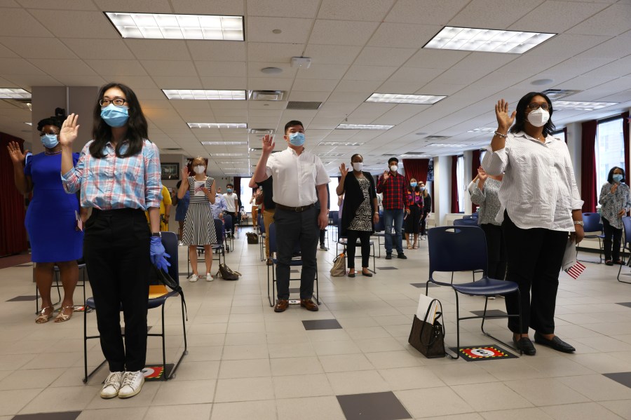 People raise their hands to take an oath during a naturalization ceremony on July 22, 2020, in New York City. (Michael M. Santiago/Getty Images)