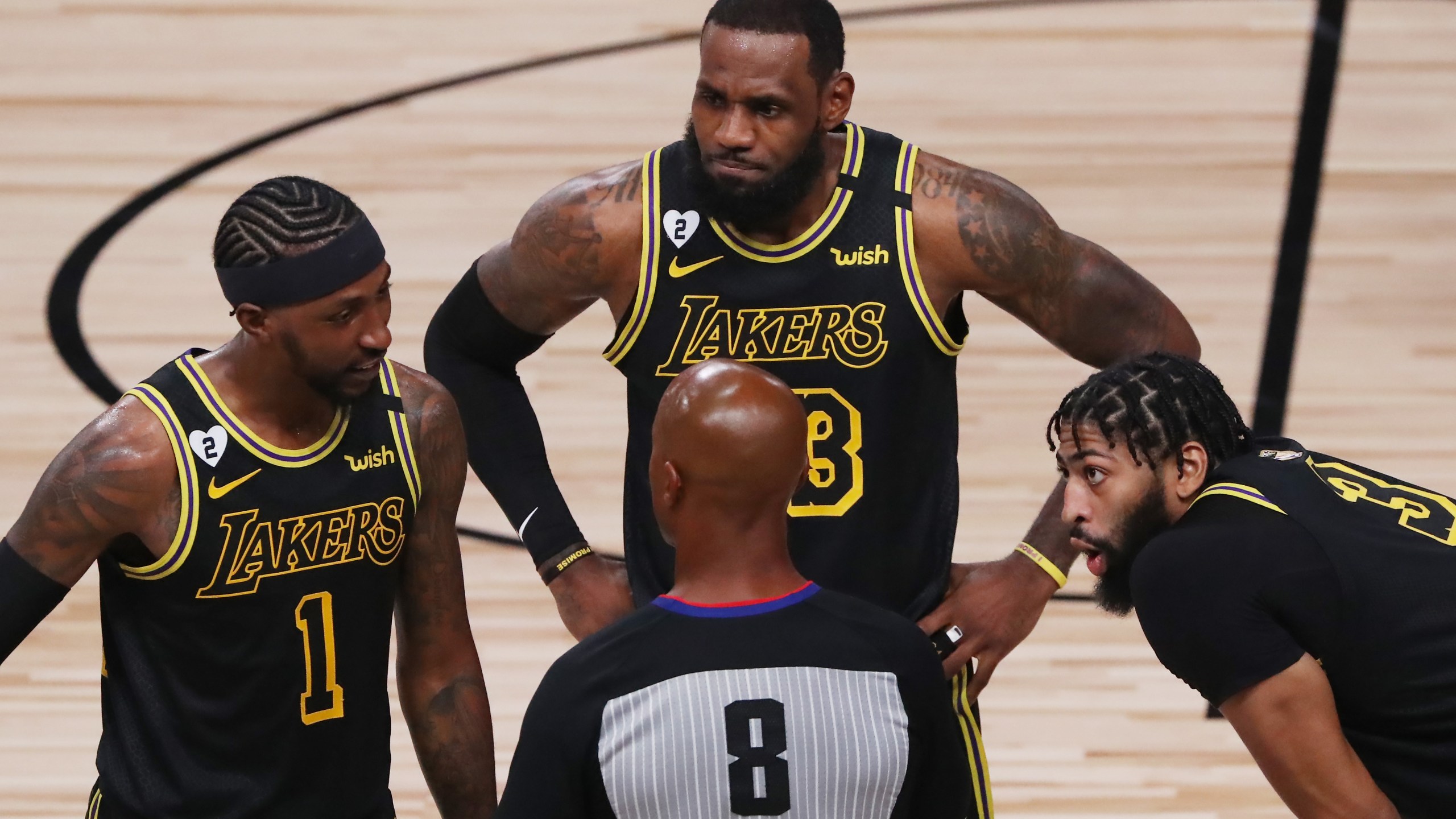 LeBron James, Kentavious Caldwell-Pope and Anthony Davis of the Los Angeles Lakers talk with referee Marc Davis during Game 5 of the 2020 NBA Finals at AdventHealth Arena at the ESPN Wide World Of Sports Complex on Oct. 9, 2020 in Lake Buena Vista, Florida. (Sam Greenwood/Getty Images)