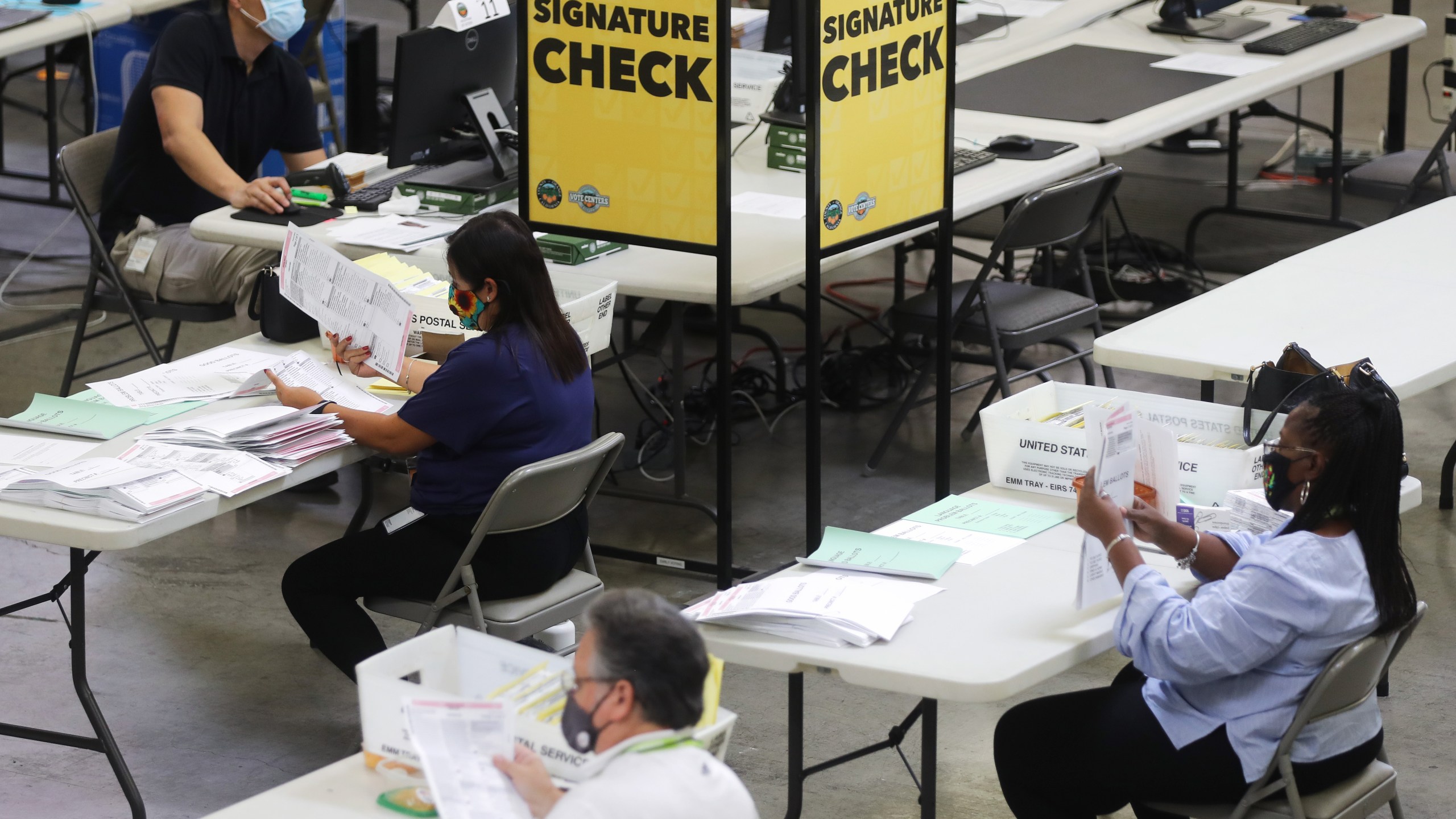 Election workers process mail-in ballots as a monitor displays a livestream of the process at the Orange County Registrar of Voters on October 19, 2020 in Santa Ana, California. (Mario Tama/Getty Images)