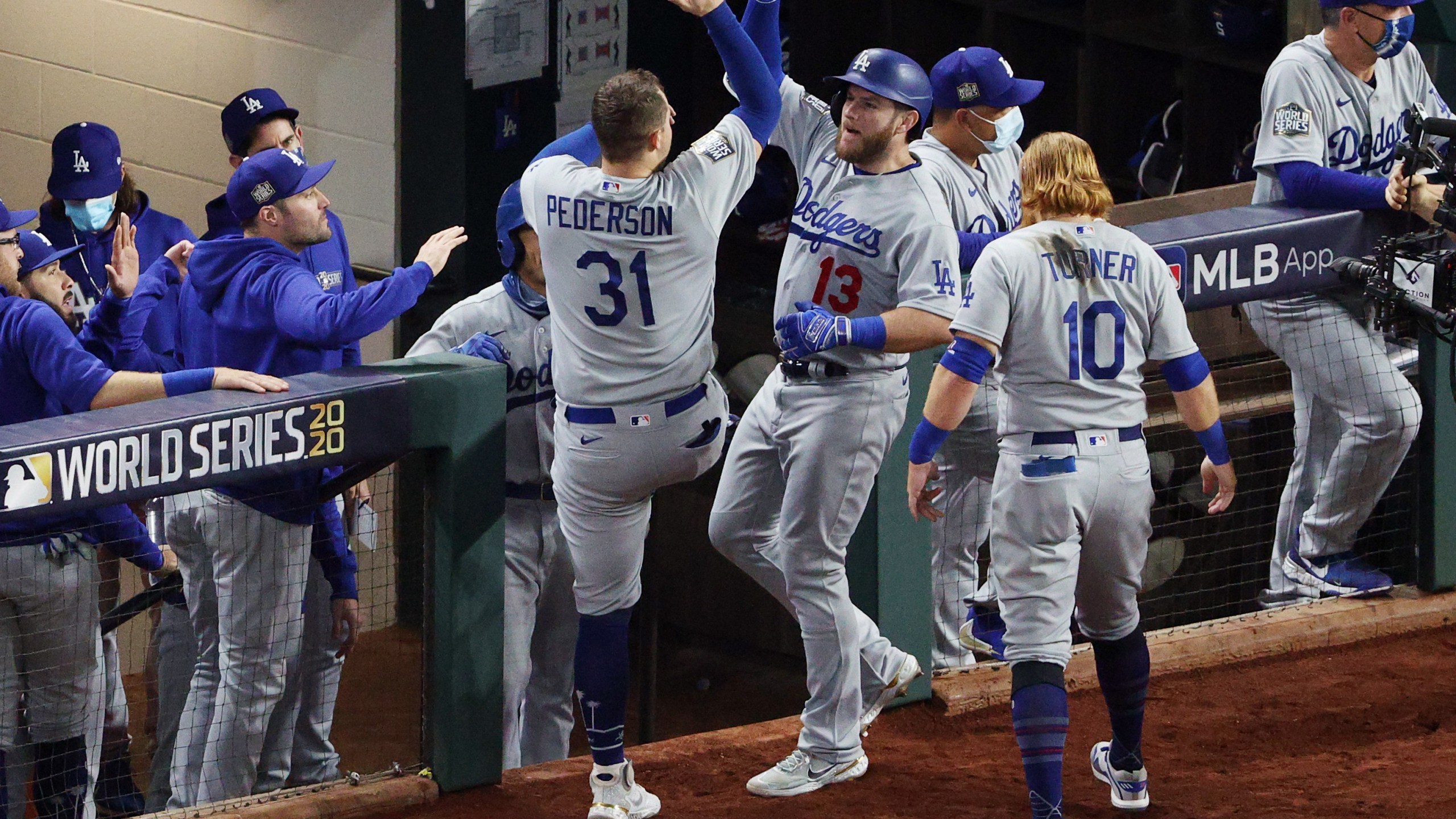 Max Muncy #13 of the Los Angeles Dodgers is congratulated by Joc Pederson #31 and Justin Turner #10 after hitting a solo home run against the Tampa Bay Rays during the fifth inning in Game Five of the 2020 MLB World Series at Globe Life Field on Oct. 25, 2020, in Arlington, Texas. (Sean M. Haffey/Getty Images)