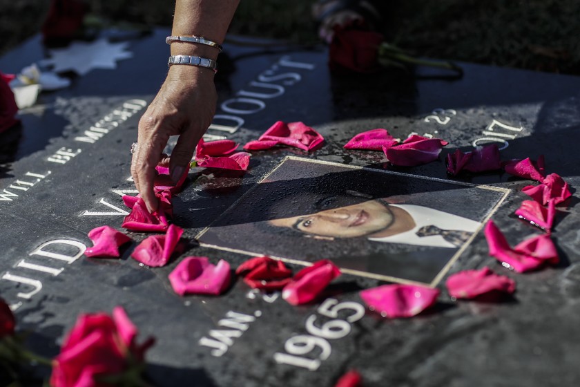 Majid Vatandoust died of colon cancer at age 52, three years after a request for a colonoscopy was denied by a specialist working for L.A. County despite tests that showed clear indicators of the disease. A woman arranges flowers at his gravestone in this undated photo. (Robert Gauthier / Los Angeles Times)