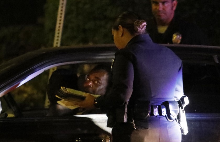 LAPD officers give a man a ticket for an expired registration in South Los Angeles on July 25, 2019.(Genaro Molina / Los Angeles Times)