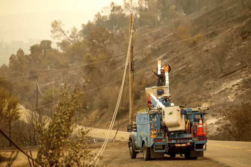 A Pacific Gas & Electric Co. worker clears a power line blocking a roadway in unincorporated Napa County on Aug. 20. PG&E is preparing for potential power shutoffs this week.(Noah Berger / Associated Press)