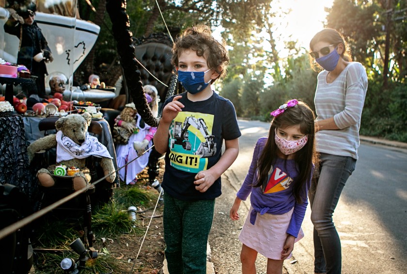 A family wears face coverings on Oct. 28, 2020 while visiting a Brentwood home that goes all out with Hollywood-caliber Halloween decorations. (Jason Armond / Los Angeles Times)