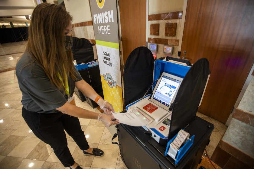 An Orange County election worker demonstrates casting a ballot at the Honda Center in Anaheim, where voters can opt to walk in or drive through starting Oct. 30.(Allen J. Schaben / Los Angeles Times)