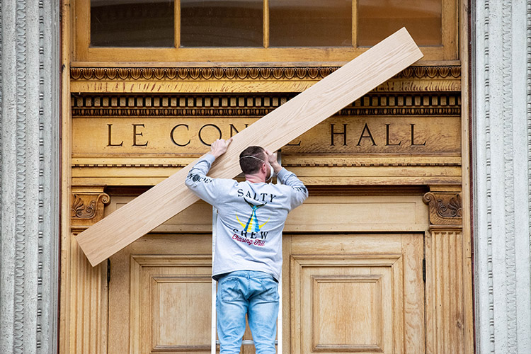 A UC Berkeley crew member covers up the words “LeConte Hall” on the academic building that has been known for nearly 100 years as Old LeConte Hall. (Irene Yi / UC Berkeley)