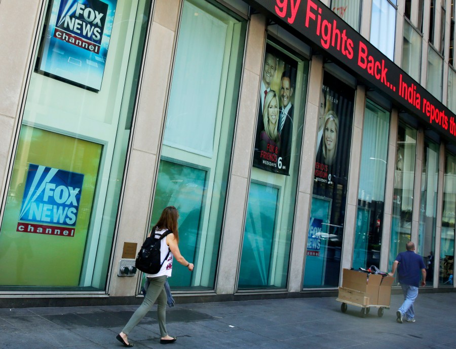 People pass the News Corporation headquarters building and Fox News studios in New York on Aug. 1, 2017. (AP Photo/Richard Drew, File)