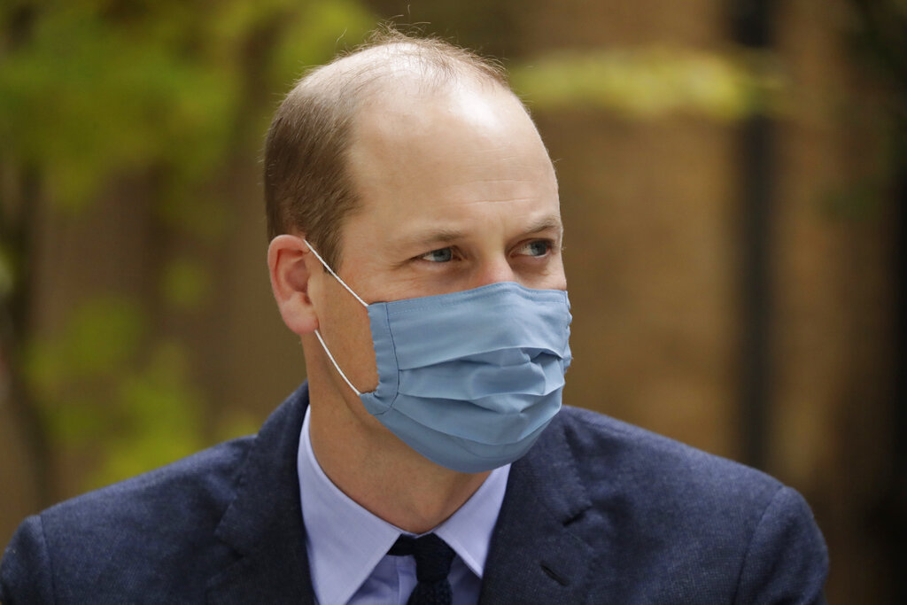 In this Oct. 20, 2020, file photo, wearing a face covering to curb the spread of coronavirus Britain's Prince William meets pharmacist Joyce Duah as he and his wife Kate the Duchess of Cambridge visit St. Bartholomew's Hospital in London, to mark the launch of the nationwide "Hold Still" community photography project. (AP Photo/Matt Dunham, Pool, File)