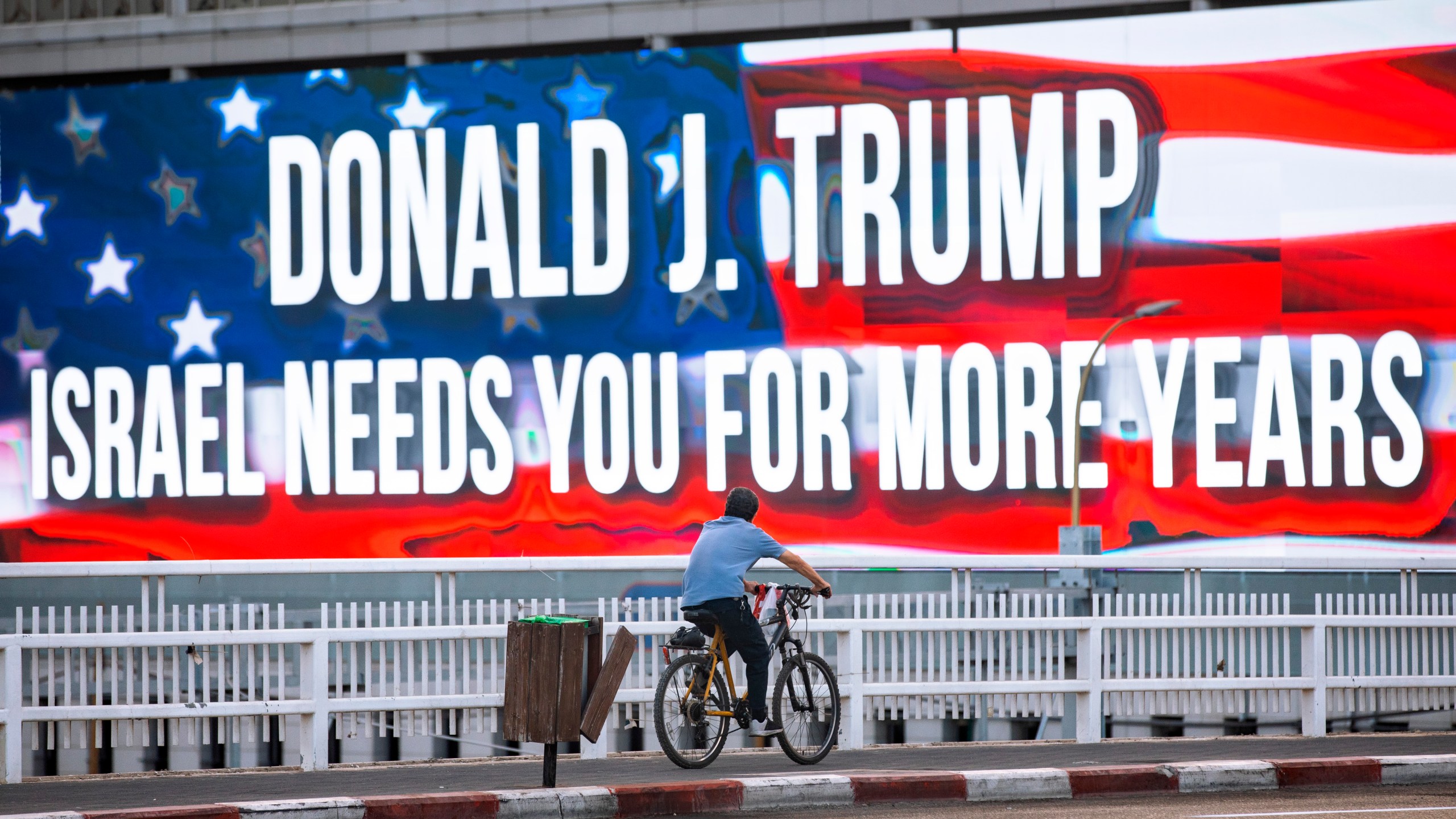 In this Oct. 21, 2020 file photo a cyclist rides next to a billboard supporting President Donald Trump in Tel Aviv ahead of the U.S presidential election. (Oded Balilty/Associated Press)