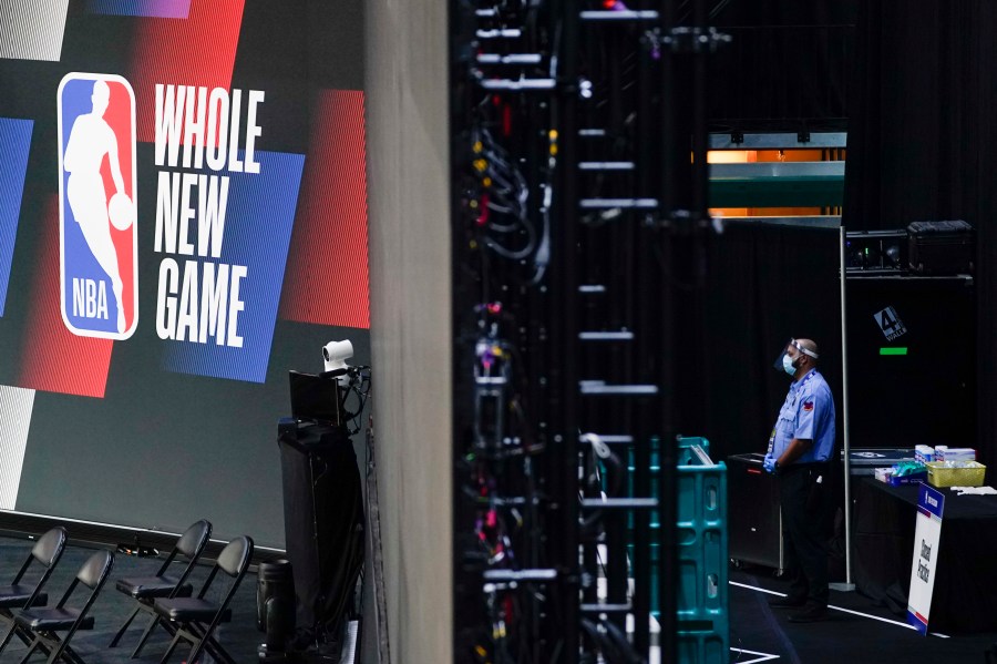 In this July 29, 2020, file photo, a security guard wearing a face mask stands near a basketball arena inside the NBA bubble at ESPN Wide World of Sports Complex in Lake Buena Vista, Fla. (AP Photo/Ashley Landis, File)