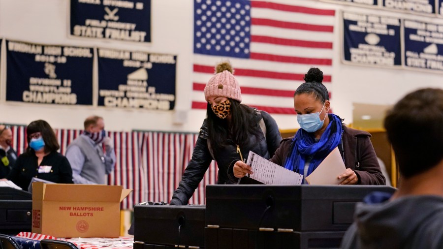 Two women, wearing protective masks due to the COVID-19 pandemic, cast their ballots at a polling station in Windham, New Hampshire, on Nov. 3, 2020. (Charles Krupa / Associated Press)