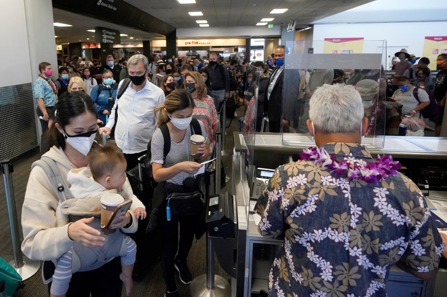 In this Oct. 15, 2020, file photo, United Airlines passengers walk past the gate to board a flight to Hawaii at San Francisco International Airport. (AP Photo/Jeff Chiu, File)