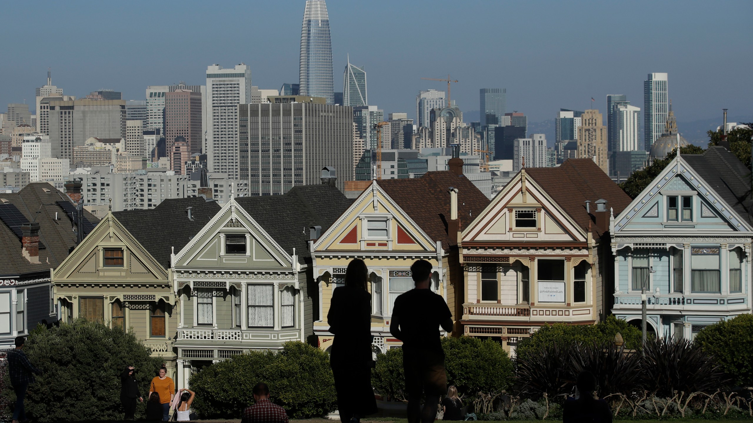 Visitors look toward the "Painted Ladies," a row of historical Victorian homes, in front of the San Francisco skyline from Alamo Square Park on Feb. 26, 2020. (Jeff Chiu / Associated Press)