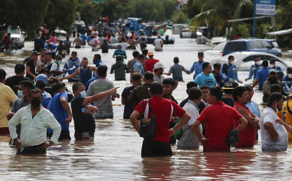 Residents wade through a flooded road in the aftermath of Hurricane Eta in Planeta, Honduras, Thursday, Nov. 5, 2020. (AP Photo/Delmer Martinez)