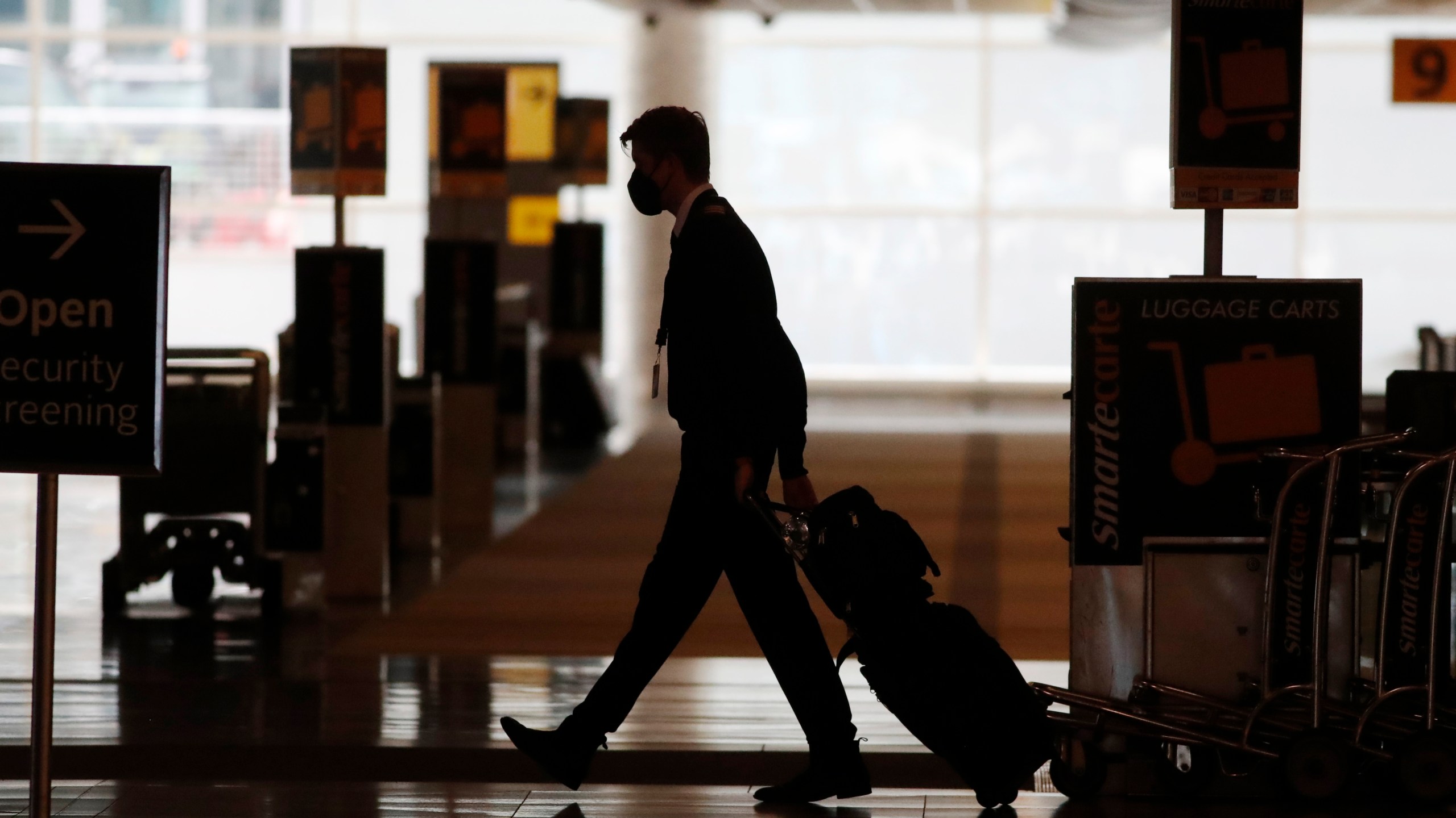 In this Thursday, April 9, 2020, file photo, a lone airline crew member pulls his bags behind him as he walks through the baggage-claim area at Denver International Airport in Denver. (David Zalubowski, File)