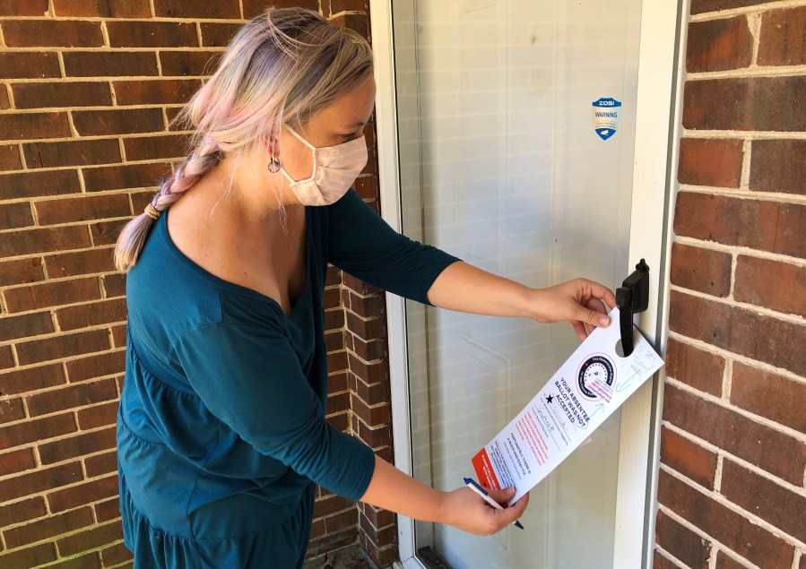 Christin Clatterbuck leaves an affidavit and information about fixing absentee ballots on the door of a home in Stone Mountain, Ga., Friday, Nov. 6, 2020. (AP Photo/Sudhin Thanawala)